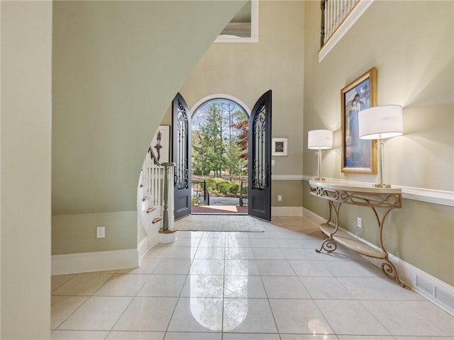 entrance foyer with a towering ceiling and light tile patterned floors