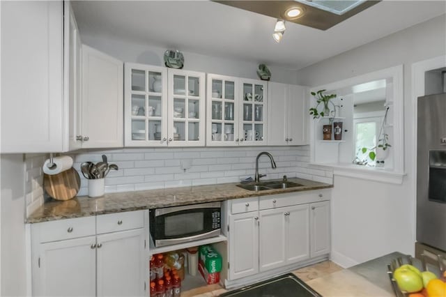 kitchen featuring white cabinetry, sink, tasteful backsplash, dark stone countertops, and appliances with stainless steel finishes