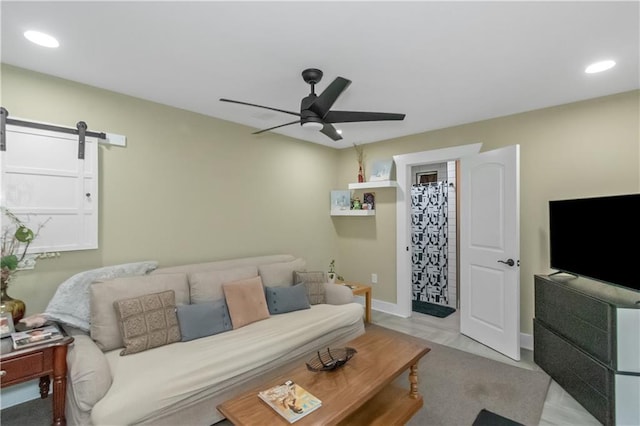 living room with a barn door and ceiling fan