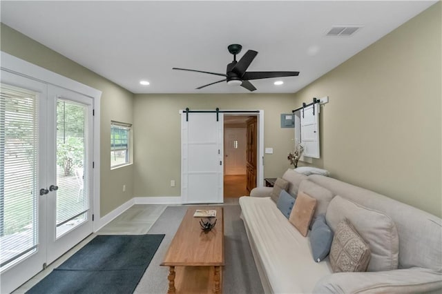 living room with ceiling fan and a barn door