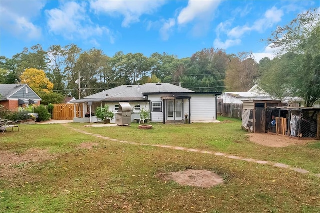 back of house with a yard and a storage shed