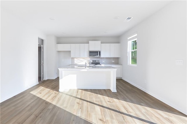 650 Cayenne Way, Lawrenceville, GA 30045 - kitchen with stainless steel appliances, a center island with sink, white cabinets, and light wood-style floors