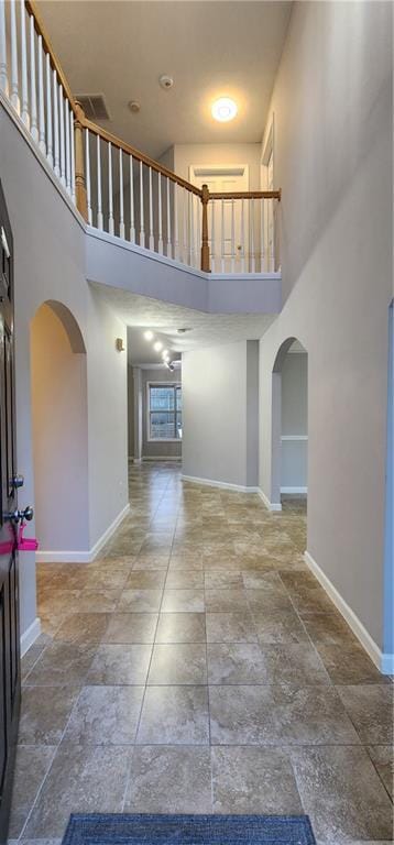 1230 Chris Lake Dr, Lawrenceville, GA 30046 - hall featuring a towering ceiling, arched walkways, baseboards, and stone tile flooring