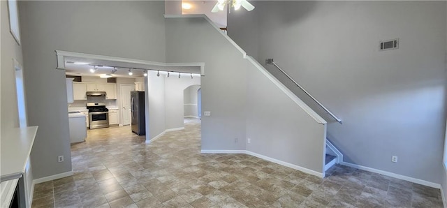 1230 Chris Lake Dr, Lawrenceville, GA 30046 - unfurnished living room featuring a ceiling fan, arched walkways, stairway, track lighting, and baseboards
