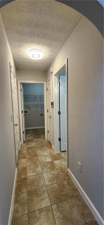 1230 Chris Lake Dr, Lawrenceville, GA 30046 - hall featuring baseboards, arched walkways, and dark stone finish floors