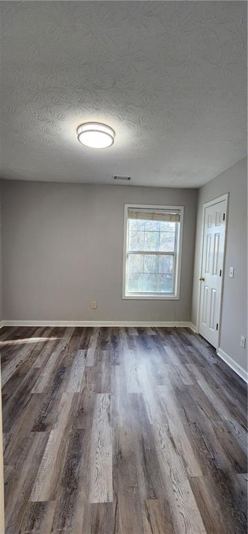 1230 Chris Lake Dr, Lawrenceville, GA 30046 - spare room featuring dark wood-style flooring, baseboards, and a textured ceiling