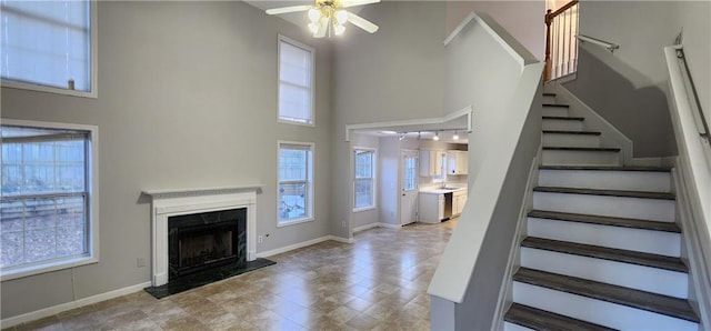 1230 Chris Lake Dr, Lawrenceville, GA 30046 - unfurnished living room featuring a towering ceiling, a ceiling fan, stairway, baseboards, and a premium fireplace
