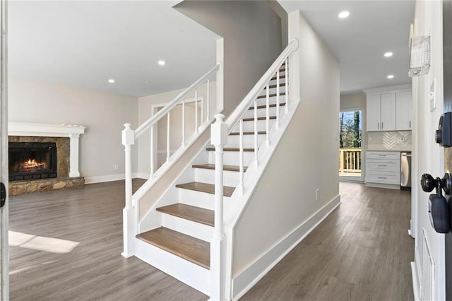 stairway featuring wood-type flooring and a fireplace