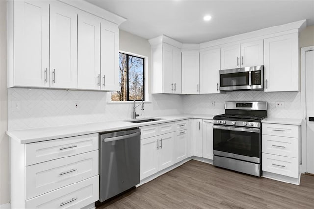 kitchen with sink, appliances with stainless steel finishes, white cabinetry, dark hardwood / wood-style floors, and tasteful backsplash