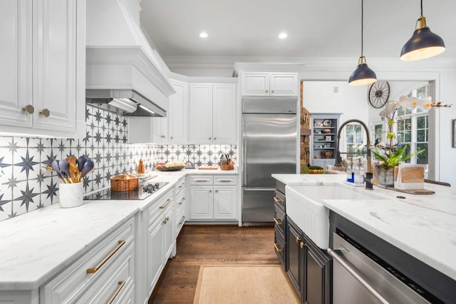 kitchen featuring white cabinets, appliances with stainless steel finishes, dark wood-type flooring, pendant lighting, and light stone counters