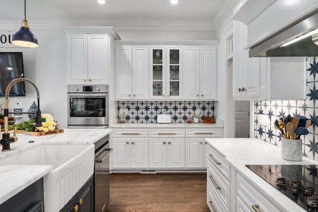 kitchen with stainless steel oven, wall chimney range hood, black electric cooktop, sink, and white cabinetry