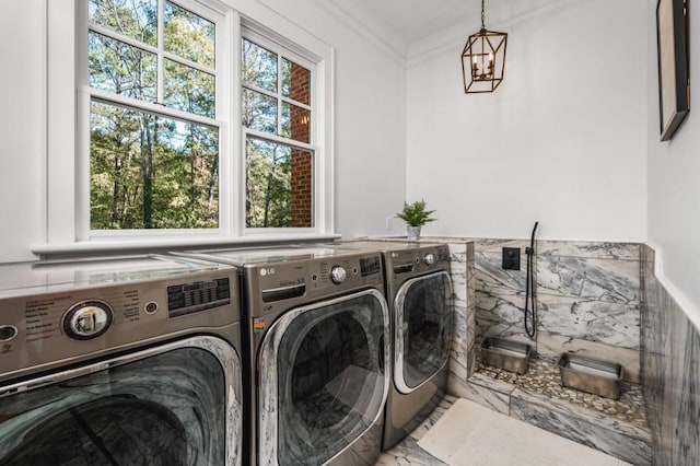 laundry area with a wealth of natural light, ornamental molding, a notable chandelier, and washing machine and dryer