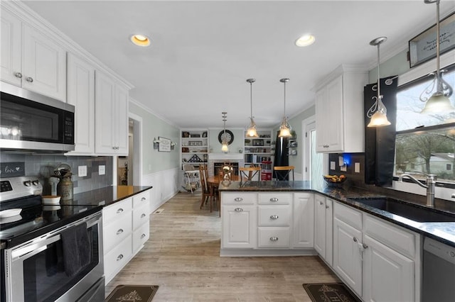 kitchen with hanging light fixtures, sink, white cabinets, and appliances with stainless steel finishes