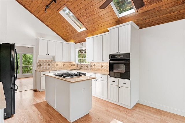 kitchen featuring black appliances, a skylight, wood ceiling, lofted ceiling, and light wood-type flooring