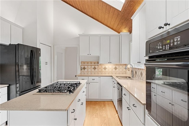 kitchen with black appliances, a sink, backsplash, light wood-style flooring, and a center island