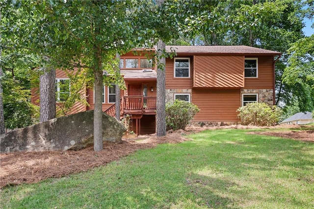 back of property featuring stone siding and a lawn