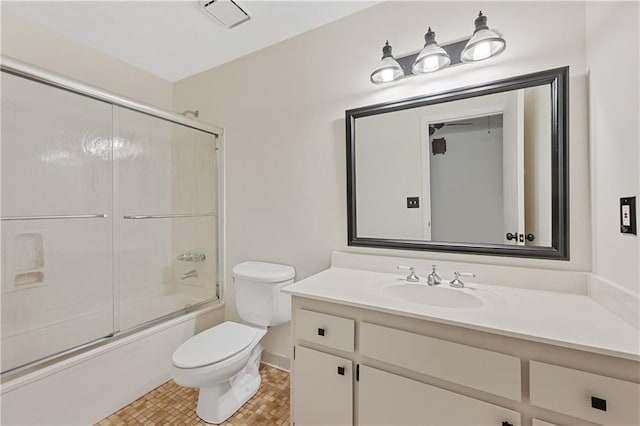 bathroom featuring toilet, vanity, bath / shower combo with glass door, and baseboards