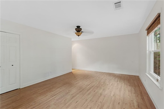 unfurnished room with light wood finished floors, a ceiling fan, and baseboards