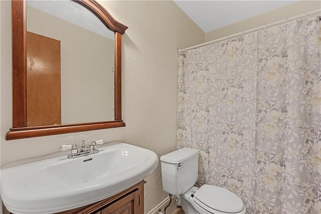 full bath featuring toilet, vanity, and a textured wall