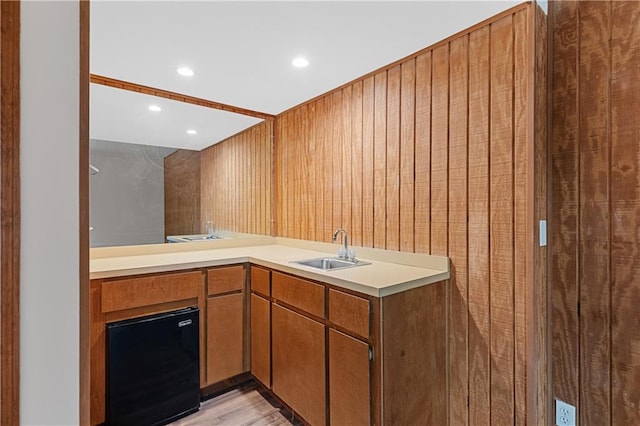 kitchen featuring a sink, light countertops, light wood-type flooring, recessed lighting, and brown cabinets