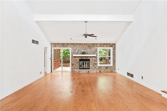 unfurnished living room featuring ceiling fan, light wood finished floors, baseboards, and a stone fireplace