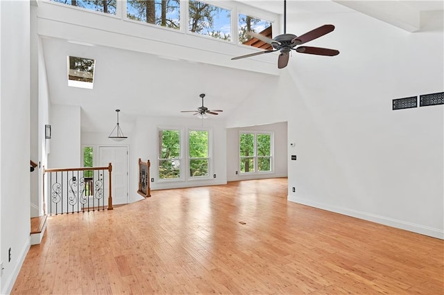 unfurnished living room featuring high vaulted ceiling, a ceiling fan, wood finished floors, baseboards, and beamed ceiling