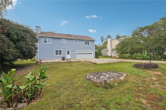 rear view of property featuring a garage, a yard, driveway, and a chimney