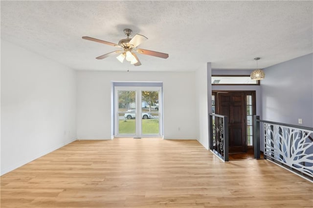 empty room featuring a textured ceiling, ceiling fan, and light wood-type flooring