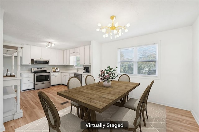 dining space featuring baseboards, light wood finished floors, and a chandelier