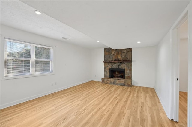 unfurnished living room featuring light wood-type flooring, baseboards, visible vents, and a fireplace