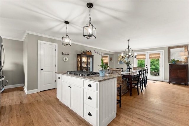 322 Windy Ridge Dr, Demorest, GA 30535 - kitchen with a kitchen bar, white cabinetry, ornamental molding, light wood finished floors, and stainless steel gas cooktop