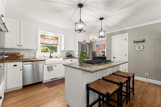 322 Windy Ridge Dr, Demorest, GA 30535 - kitchen with stainless steel appliances, light wood finished floors, decorative backsplash, white cabinets, and a kitchen island