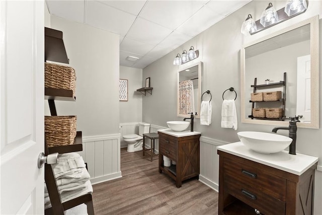 322 Windy Ridge Dr, Demorest, GA 30535 - bathroom featuring two vanities, a drop ceiling, wood finished floors, a wainscoted wall, and a decorative wall