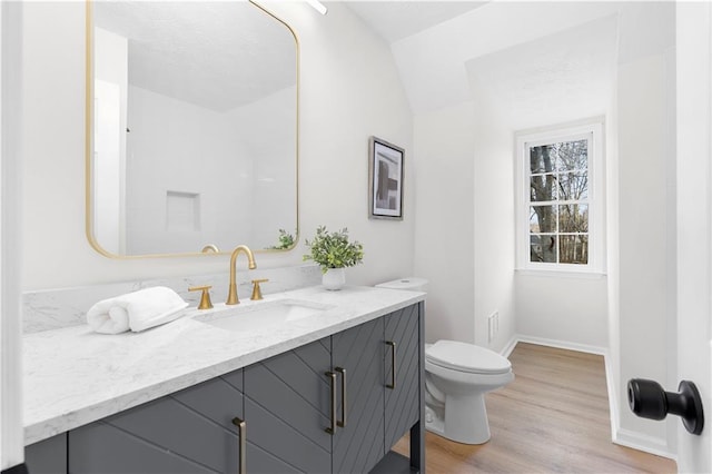 bathroom with lofted ceiling, vanity, toilet, and hardwood / wood-style floors