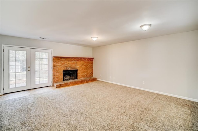 unfurnished living room featuring a brick fireplace, carpet, and french doors