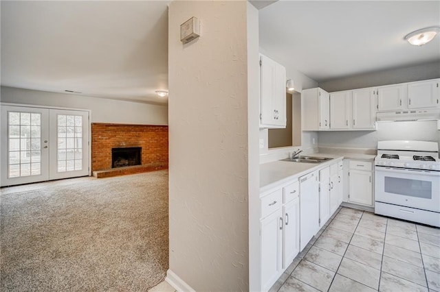 kitchen with sink, white cabinetry, a brick fireplace, light carpet, and white appliances