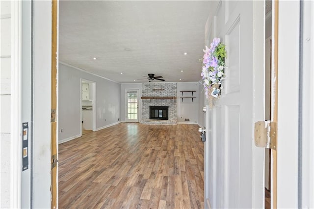 120 Lakeside Dr, Ellenwood, GA 30294 - unfurnished living room featuring a ceiling fan, a fireplace, wood finished floors, and ornamental molding