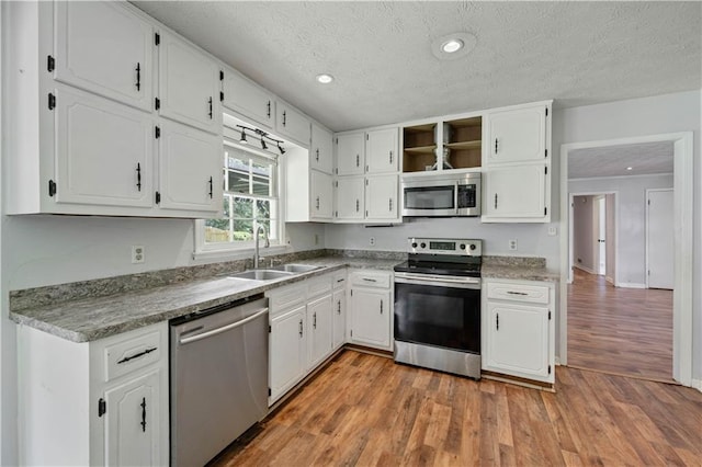 120 Lakeside Dr, Ellenwood, GA 30294 - kitchen with stainless steel appliances, open shelves, light wood-style floors, white cabinetry, and a textured ceiling