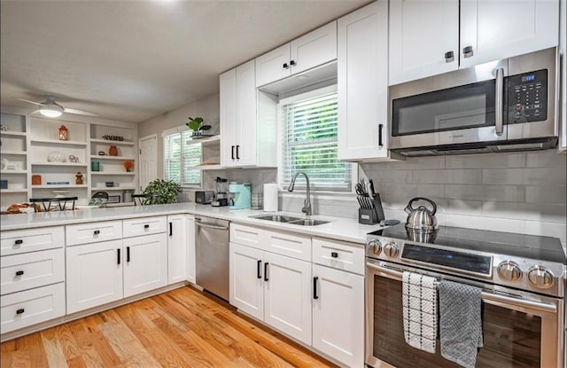 kitchen with stainless steel appliances, a sink, a ceiling fan, white cabinets, and tasteful backsplash