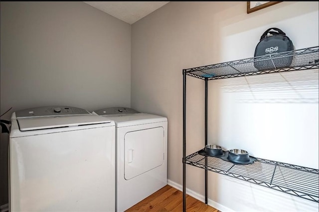 laundry room featuring separate washer and dryer, light wood finished floors, and baseboards