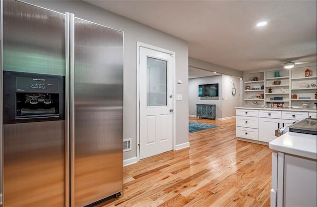 kitchen with stainless steel refrigerator with ice dispenser, white cabinets, open shelves, light wood-style flooring, and light countertops