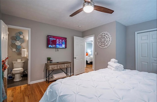 bedroom with light wood-style flooring, a closet, baseboards, a ceiling fan, and ensuite bath