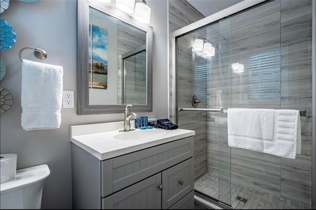 bathroom with a stall shower, vanity, and toilet