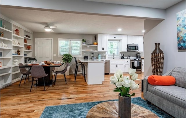 living area featuring light wood-style flooring, ceiling fan, and recessed lighting