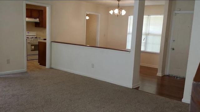 carpeted empty room with an inviting chandelier