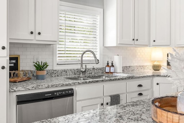 kitchen with backsplash, stainless steel dishwasher, white cabinetry, a sink, and light stone countertops