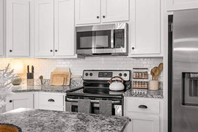 kitchen with appliances with stainless steel finishes, white cabinetry, and backsplash