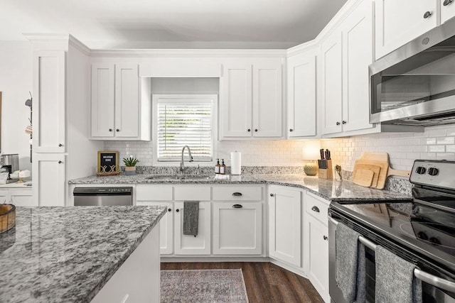 kitchen featuring light stone counters, a sink, white cabinetry, appliances with stainless steel finishes, and dark wood-style floors