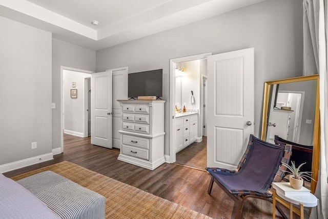 bedroom featuring dark wood finished floors, connected bathroom, and baseboards