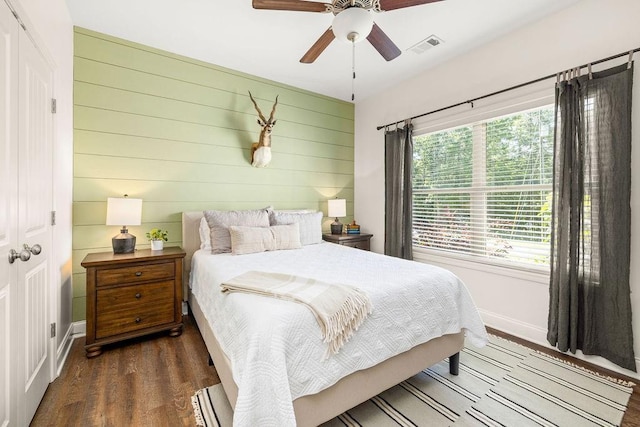 bedroom with a ceiling fan, baseboards, visible vents, and wood finished floors